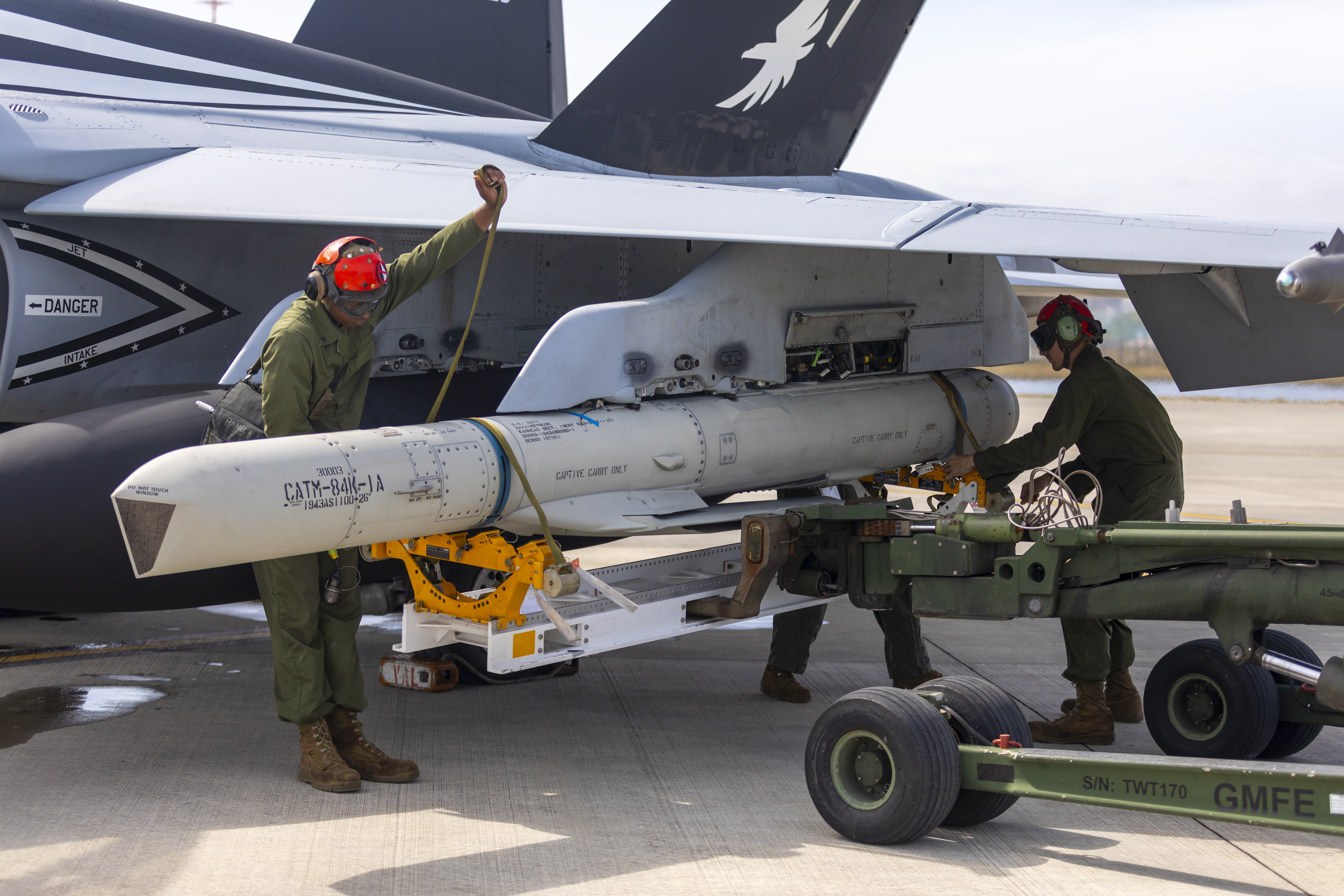 U.S. Marines with Marine Fighter Attack Squadron (VMFA) 115 prepare to remove an ATM-84K SLAM-ER missile from an F/A-18D Hornet aircraft during a hot loading validation event at Marine Corps Air Station Iwakuni, Japan, March 24, 2023. Marines with VMFA-115 conducted the first ever hot load of an AGM-84D Harpoon missile during a validation event. The validation further enables loading of different types of ordnance while the aircraft is running, giving greater capability and increased sortie generation of tactical aircraft in the Indo-Pacific. (U.S. Marine Corps photo by Cpl. Tyler Harmon)